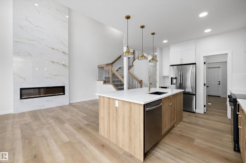 High-ceiling living area with a floor-to-ceiling fireplace featuring a linear electric insert - 1780 Crossbill Loop Nw, Edmonton, AB 