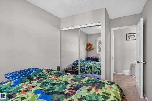 Mirrored sliding closet doors with an interior window reflection, light grey painted walls, and textured ceiling finish - 18319 93 Avenue Nw, Edmonton, AB 
