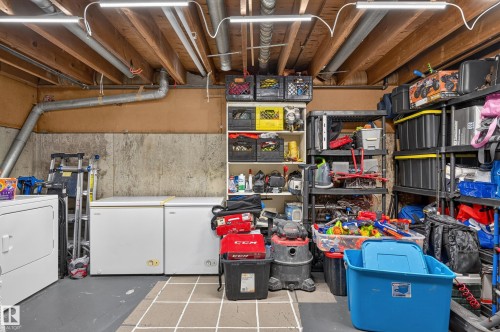 Concrete foundation walls, exposed ceiling joists, overhead strip lighting, and a washer appliance - 18319 93 Avenue Nw, Edmonton, AB 