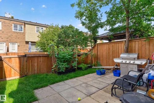 Private backyard featuring a paved patio area, green lawn, and wood privacy fencing - 18319 93 Avenue Nw, Edmonton, AB 