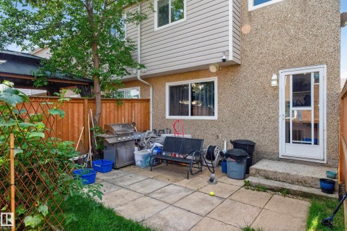 Private fenced yard with patio, mature trees, and exterior wall sconce lighting - 18319 93 Avenue Nw, Edmonton, AB 
