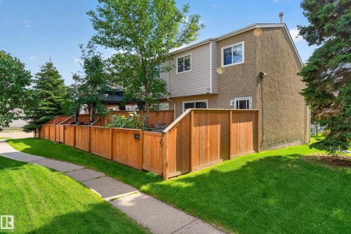 Stucco and siding exterior with multiple windows, wooden privacy fencing, and a paved walkway - 18319 93 Avenue Nw, Edmonton, AB 