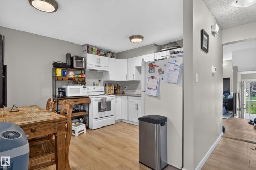 Kitchen featuring wood-finish flooring, white cabinetry, light-toned countertops, and ceiling-mounted lighting fixtures - 18319 93 Avenue Nw, Edmonton, AB 