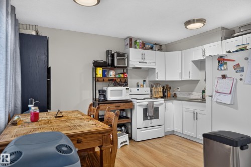 White cabinetry, wood-finish flooring, white appliances, and ceiling-mounted lighting - 18319 93 Avenue Nw, Edmonton, AB 