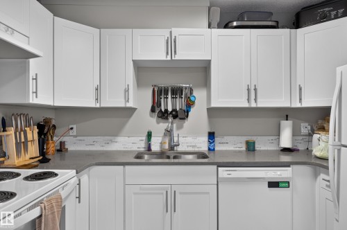 White shaker-style cabinetry with brushed nickel hardware, light grey countertops, and a white tile backsplash - 18319 93 Avenue Nw, Edmonton, AB 
