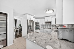 Kitchen featuring white cabinetry, stainless steel appliances, granite countertops, and a tiled backsplash - 