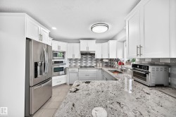 White shaker-style cabinetry, stainless steel appliances, granite countertops, tile flooring, and a subway tile backsplash - 