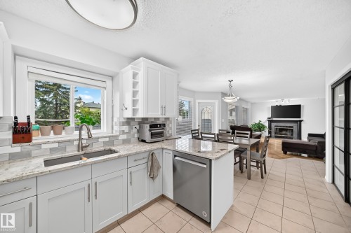 Kitchen featuring light-toned cabinetry, a stainless steel sink with a gooseneck faucet, light-toned countertops, and a tiled backsplash - 4216 47 Street Nw, Edmonton, AB 