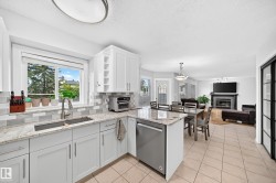 Kitchen featuring light-toned cabinetry, a stainless steel sink with a gooseneck faucet, light-toned countertops, and a tiled backsplash - 