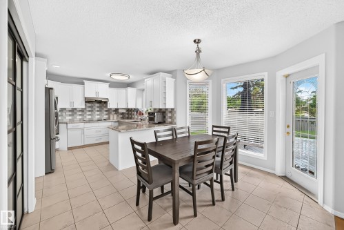 Kitchen featuring white cabinetry, tile backsplash, island with countertop, and tile flooring - 4216 47 Street Nw, Edmonton, AB 
