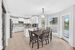 Kitchen featuring white cabinetry, tile backsplash, island with countertop, and tile flooring - 