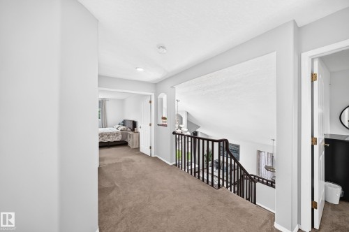 Carpeted hallway with painted walls, arched alcove, and open railing overlooking the space below - 4216 47 Street Nw, Edmonton, AB 