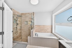 Glass-enclosed shower with stone tile surround, built-in recessed shelving, and a separate built-in bathtub - 