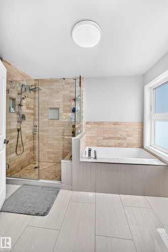Glass-enclosed shower with tiled surround, integrated soaking tub, and large format floor tiling - 4216 47 Street Nw, Edmonton, AB 