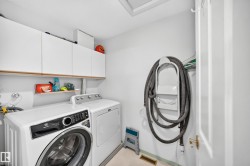 Integrated laundry space with built-in overhead cabinetry, an open shelf, and white walls - 
