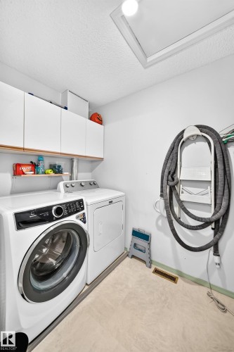 White cabinetry with wood-finish trim, overhead light fixture, and light-toned flooring - 4216 47 Street Nw, Edmonton, AB 
