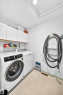 White cabinetry with wood-finish trim, overhead light fixture, and light-toned flooring - 