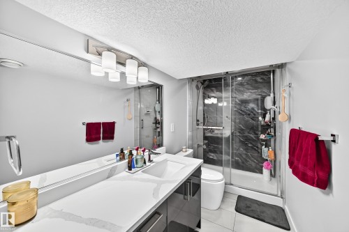 Spacious bathroom featuring a single vanity with an integrated sink, a large wall-mounted mirror, and a contemporary light fixture - 4216 47 Street Nw, Edmonton, AB 