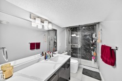 Spacious bathroom featuring a single vanity with an integrated sink, a large wall-mounted mirror, and a contemporary light fixture - 