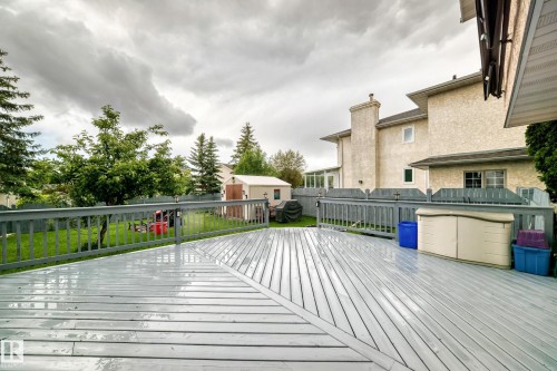Expansive wood deck with painted railing, mature trees, and a manicured lawn - 4216 47 Street Nw, Edmonton, AB 