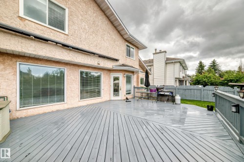 Expansive wooden deck with a gray finish, featuring a privacy fence and exterior lighting fixtures - 4216 47 Street Nw, Edmonton, AB 