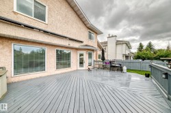 Expansive wooden deck with a gray finish, featuring a privacy fence and exterior lighting fixtures - 