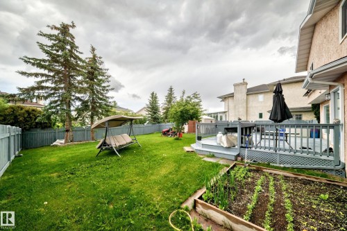 Expansive backyard featuring a raised garden bed, mature evergreen trees, and a multi-level deck with a railing system - 4216 47 Street Nw, Edmonton, AB 