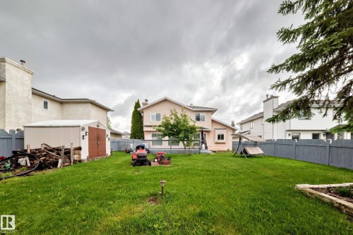 Expansive backyard with a wooden fence, storage shed, and a stone-edged garden bed - 4216 47 Street Nw, Edmonton, AB 