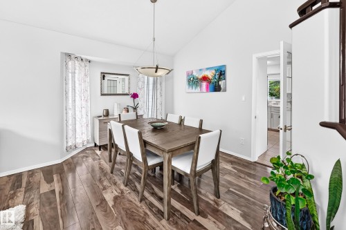 Vaulted ceiling with a contemporary pendant light fixture, wood-finish flooring, and a doorway with glass paneling - 4216 47 Street Nw, Edmonton, AB 