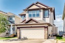 Two-story exterior with light siding, a shingled roof, a stone-clad garage base, an attached two-car garage, and multiple windows - 2812 12 Street Nw, Edmonton, AB 