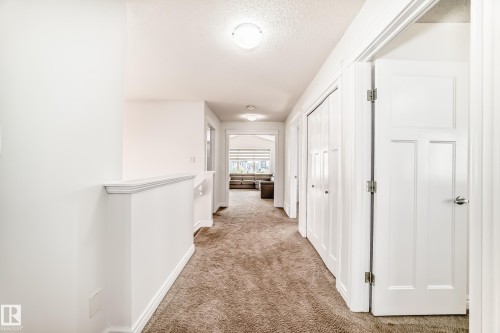 Hallway featuring carpeted flooring, white walls, flush mount lighting, and panel doors - 2812 12 Street Nw, Edmonton, AB 