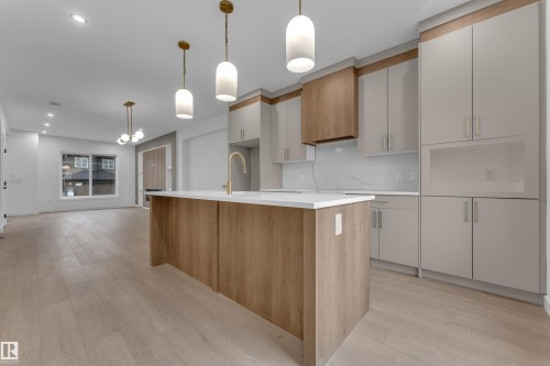 Kitchen island with white countertop, brass-finish faucet, and wood-finish paneling - 265 Falcon Crescent, Leduc, AB 