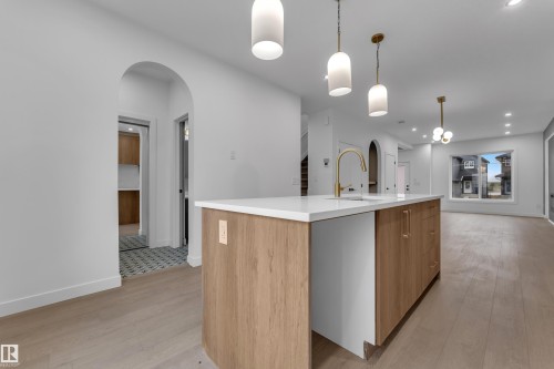 Kitchen island with wood-finish cabinetry, white countertop, and gold-finish faucet - 265 Falcon Crescent, Leduc, AB 