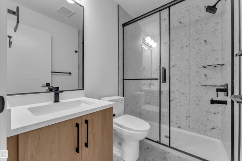 Contemporary bathroom featuring a wood-finish vanity, integrated sink, and matte black fixtures - 265 Falcon Crescent, Leduc, AB 