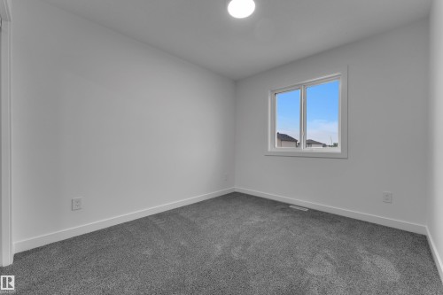 Neutral wall color, grey carpet, and a single window with white trim - 265 Falcon Crescent, Leduc, AB 