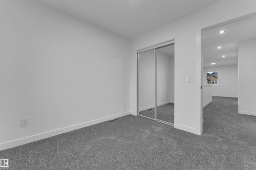 Gray carpeting, white walls, and a mirrored sliding closet door - 265 Falcon Crescent, Leduc, AB 