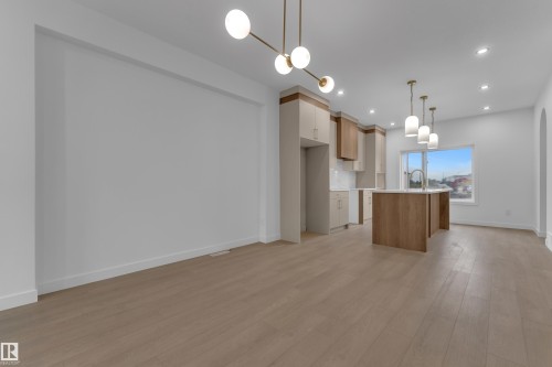 Open-concept living area featuring wood-finish flooring, recessed lighting, and a linear chandelier - 265 Falcon Crescent, Leduc, AB 
