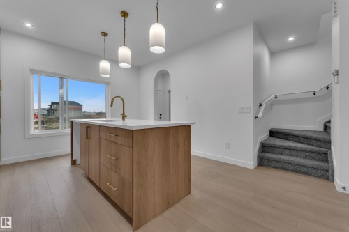 Kitchen island with wood-finish cabinetry, white countertop, and brass-finish faucet - 265 Falcon Crescent, Leduc, AB 
