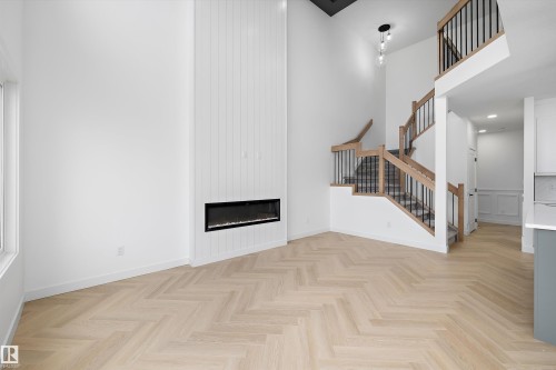 High ceilings, herringbone wood-finish flooring, and a linear electric fireplace with vertical paneling - Edmonton, AB 