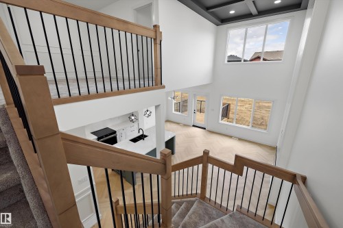 Two-story ceiling, coffered ceiling, multiple large windows, wood-finish flooring with a herringbone pattern, open-concept design - Edmonton, AB 