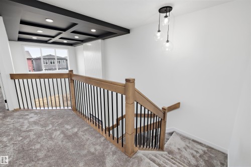 Coffered ceiling with recessed lighting, large windows, wood-finish railing with black metal balusters, and a contemporary pendant light fixture - Edmonton, AB 