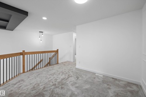 Carpeted open area with wooden handrail and black metal balusters - Edmonton, AB 