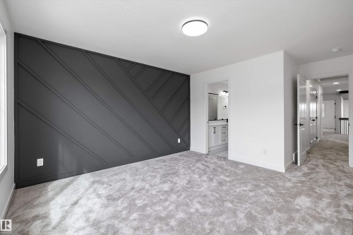 Geometric accent wall, light gray carpeting, flush-mount ceiling light, white interior doors, and a bathroom vanity with a mirror - Edmonton, AB 