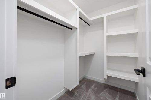 Walk-in closet with built-in shelving, white painted walls, and black hardware accents - Edmonton, AB 
