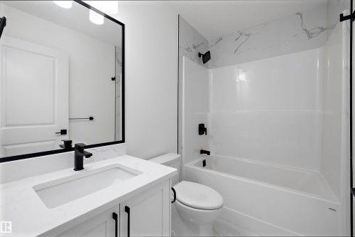 Bathroom featuring a white vanity with integrated sink, stone-finish countertop, and matte black fixtures - Edmonton, AB 
