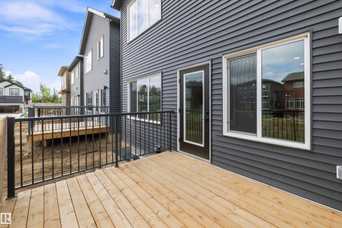 Wood-plank deck with black metal railings, gray siding exterior, and a glass-paneled door - Edmonton, AB 