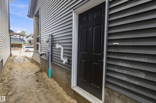 Dark paneled entry door with white trim, gray horizontal siding, and a concrete foundation - Edmonton, AB 