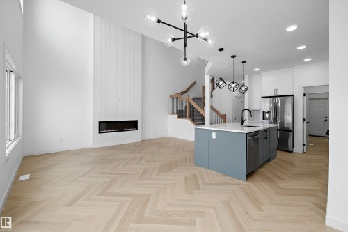 Open-concept living space featuring a tall ceiling, wood-finish herringbone flooring, and a linear fireplace - Edmonton, AB 
