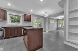 Spacious kitchen featuring dark wood cabinetry, a central island with a granite-style countertop, and stainless steel appliances - 