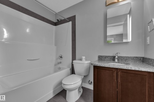 Full bathtub with integrated shower, accented by dark wall tiling - 12221 117 Avenue Nw, Edmonton, AB - Indoor Photo Showing Bathroom